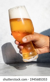 Hand Holding A Glass With Frothy IPA Beer On A Hot Day