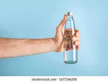 Hand Holding Glass Water Bottle On Blue Background