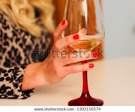 Girl’s hand holding a glass of white wine