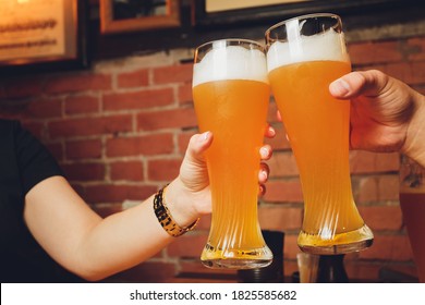 Hand Holding Glasses Of Beer Clinking Together At Outdoor Resturant.