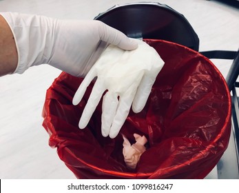 Hand holding with gloves and disposable examination gloves in the biohazard autoclave bag and garbage bag infected. Medical and healthcare concept.