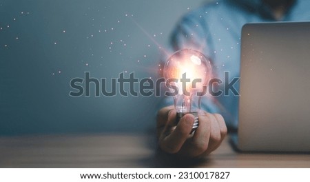 Hand holding the glowing lightbulb that is illuminating for creative thinking idea of problem solving , patent and innovation concept.