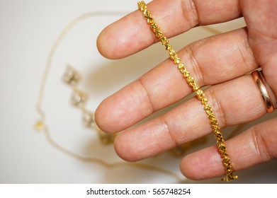 Hand Holding Gold Bracelet Isolated On White Background