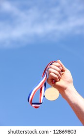 Hand Holding Gold Medal