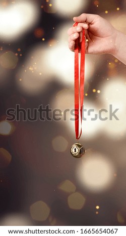 Hand holding gold medal on bokeh background. The winner and successful concept
