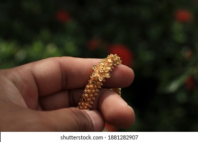 Hand Holding A Gold Necklace In The Garden