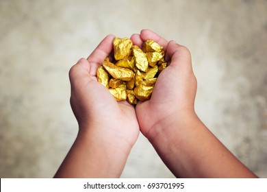 Hand Holding Gold Nugget Grains.