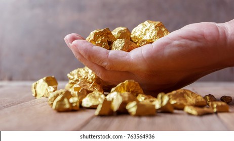 Hand Holding Gold Nugget Grains.