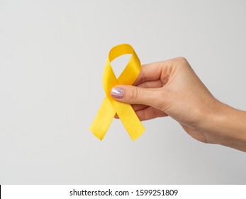 Hand holding gold ribbon on white background. International Childhood Cancer Day. February 15 symbol