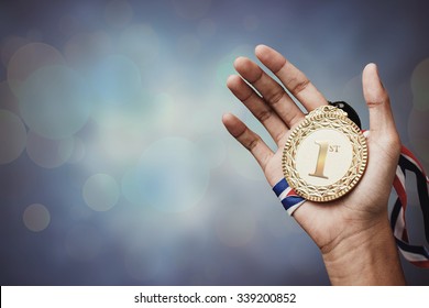 hand holding up a gold trophy cup as a winner in a competition - Shutterstock ID 339200852