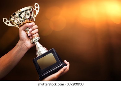 hand holding up a gold trophy cup as a winner in a competition - Shutterstock ID 339200933