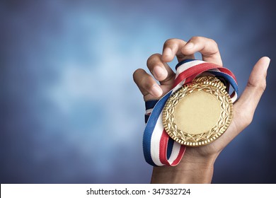 hand holding up a gold trophy cup/ medal as a winner in a competition - Shutterstock ID 347332724