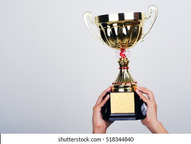 Hand Holding Up A Gold Trophy Cup As A Winner In A Competition