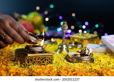 Hand Holding Golden Brass Diya Deep Being Lit On Flower Bed Decoration And Bokeh Effect For Diwali Puja New Year Deepawali Or Shubh Deepavali Navratra Pooja Festival Celebration