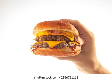 Hand Holding A Gourmet Brioche Cheese Burger With Queso Sauce Isolated On A White Background