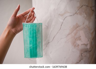 A Hand Holding Green Disposable Single Use Surgical Mask To Beat Virus On A Simple White Minimalist Background