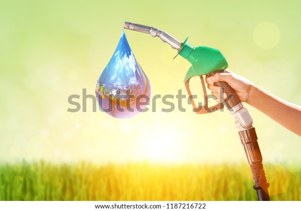 Hand holding a Green Green gas nozzle  on\
Green nature background.