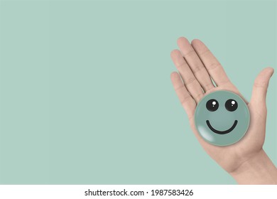 Hand holding a green icon of smile face, positive thinking, mental health concept - Shutterstock ID 1987583426