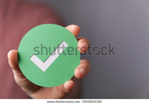 Une main tenant un papier vert avec la marque de contrôle dessus