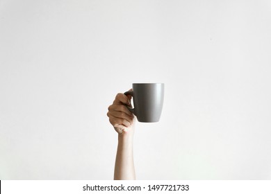 Hand Holding A Grey Cup Of Coffe Om White Background. Concept Of Sleepy Morning. Copy Space