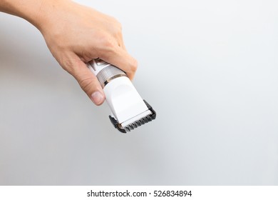 Hand Holding Hair Clippers On Grey Background