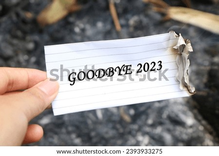 Hand holding half burnt note with writing Bye 2023. new life and new year 2024 concept. 2023 paper on fire, say goodbye to 2023