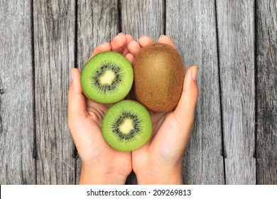 Hand holding half kiwi fruits on wooden table background - Powered by Shutterstock