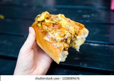 Hand Holding Half A Philadelphia Cheese Steak Sandwich (vegan) Against A Dark Navy Blue Background