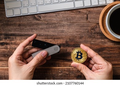 hand holding hardware wallet and transfer bitcoin and ethereum crypto currency to wallet for safety - Shutterstock ID 2107760144