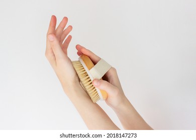 Hand Is Holding Hatural Wooden Body Brush In Front Of White Background. Woman Scrubbing Her Hand. Massage, Relax, Spa. Eco-friendly, Zero Waste Product. Beauty, Skincare, Wellness Concept