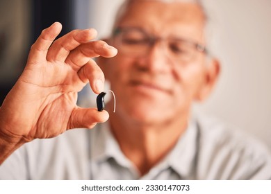 Hand holding hearing aid, senior man and tech for ears, health and wellness for retirement in nursing home. Elderly person with disability, audio or sound technology to listen in closeup at house - Powered by Shutterstock