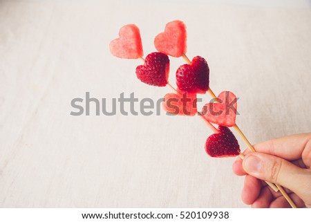 hand holding heart shape strawberry and watermelon fruit screwers