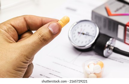 Hand Holding High Blood Pressure Medication, Pill Or Pill, Medical Tests And Sphygmomanometer In The Background