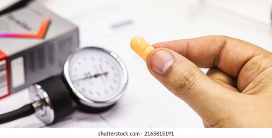 Hand Holding High Blood Pressure Medication, Pill Or Pill, Medical Tests And Sphygmomanometer In The Background