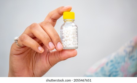Hand Holding homeopathy prescription bottle in hand 
