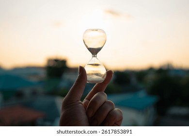 Hand holding a Hourglass with cityscape and buildings in the morning background with sun light. The concept of modern life, business, time, management and city life. - Powered by Shutterstock - Get 15% off with code: PIKWIZARD15