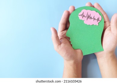 Hand holding human head profile cutout with healthy brain. Care for good memory, ADHD, Alzheimer, stroke, dementia prevention and world mental health day awareness concept. - Shutterstock ID 2116103426