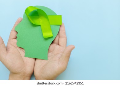 Hand Holding Human Head Profile With Lime Green Awareness Ribbon On Brain. Lyme Disease, Psychosis, Childhood Mental Illness, Lymphoma And Postpartum Depression Care Concept.