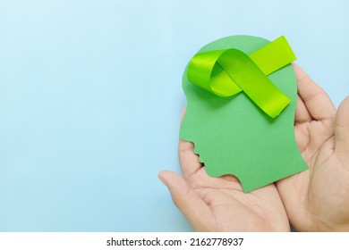 Hand Holding Human Head Profile With Lime Green Awareness Ribbon On Brain. Lyme Disease, Psychosis, Childhood Mental Illness, Lymphoma And Postpartum Depression Care Concept.