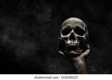 Hand holding human skull over black background - Shutterstock ID 1532505227