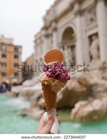 Hand holding an ice cream in a fountain in Rome, Italy. Fontana di Trevi historical monument in the Italian city center. Tourist traveling in Europe in summer