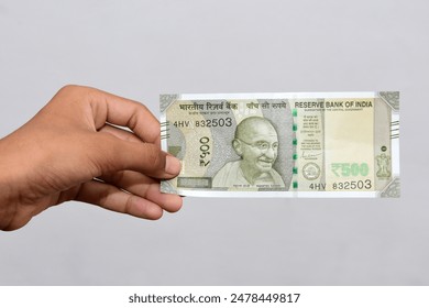 Hand Holding Indian currency 500 Rupees bank note. Giving 500 rupees note by hand