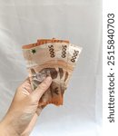 hand holding an indonesian banknote 5000 rupiah. bank concept, giving concept, holding rupiah money