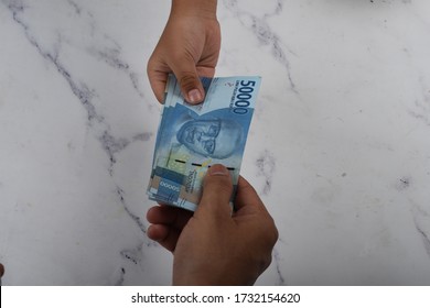 Hand holding indonesian money Rupiah (THR  tunjangan hari raya ) is holiday allowance in eid al fitri idul fitri or eid mubarak bonuses 