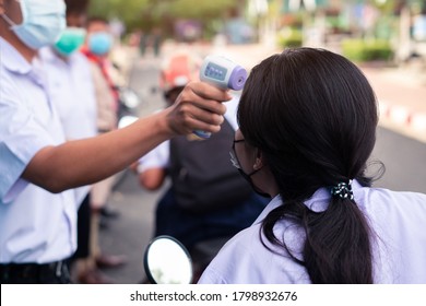 Hand Holding Infrared Thermometer Gun Forehead Temperature Test To Check Student For Protect Virus Covid-19 Symptoms In The School