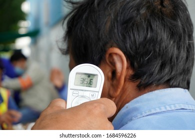 Hand Holding Infrared Thermometer To Measuring Temperature On  The Side Of The Face Of The Worker Before Entering The Chemical Industrial Plant In Construction Area. Covid Flu Screening 19 Concept.