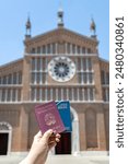 Hand holding Italian and Brazilian passports with an Italian urban landscape in the background