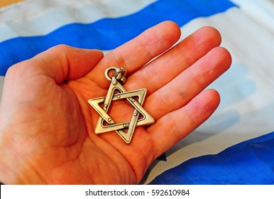 Hand holding a Jewish Star of David with Israel flag on the background. Judaism conversion concept. Hebrew kosher stock image. Israel Independence Day, Yom hazikaron, Yom haatzmaut, Yom hashoah.