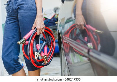 Hand holding jumper cable for recharge the battery car