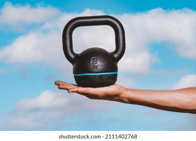 Hand Holding Kettlebell Against Sky